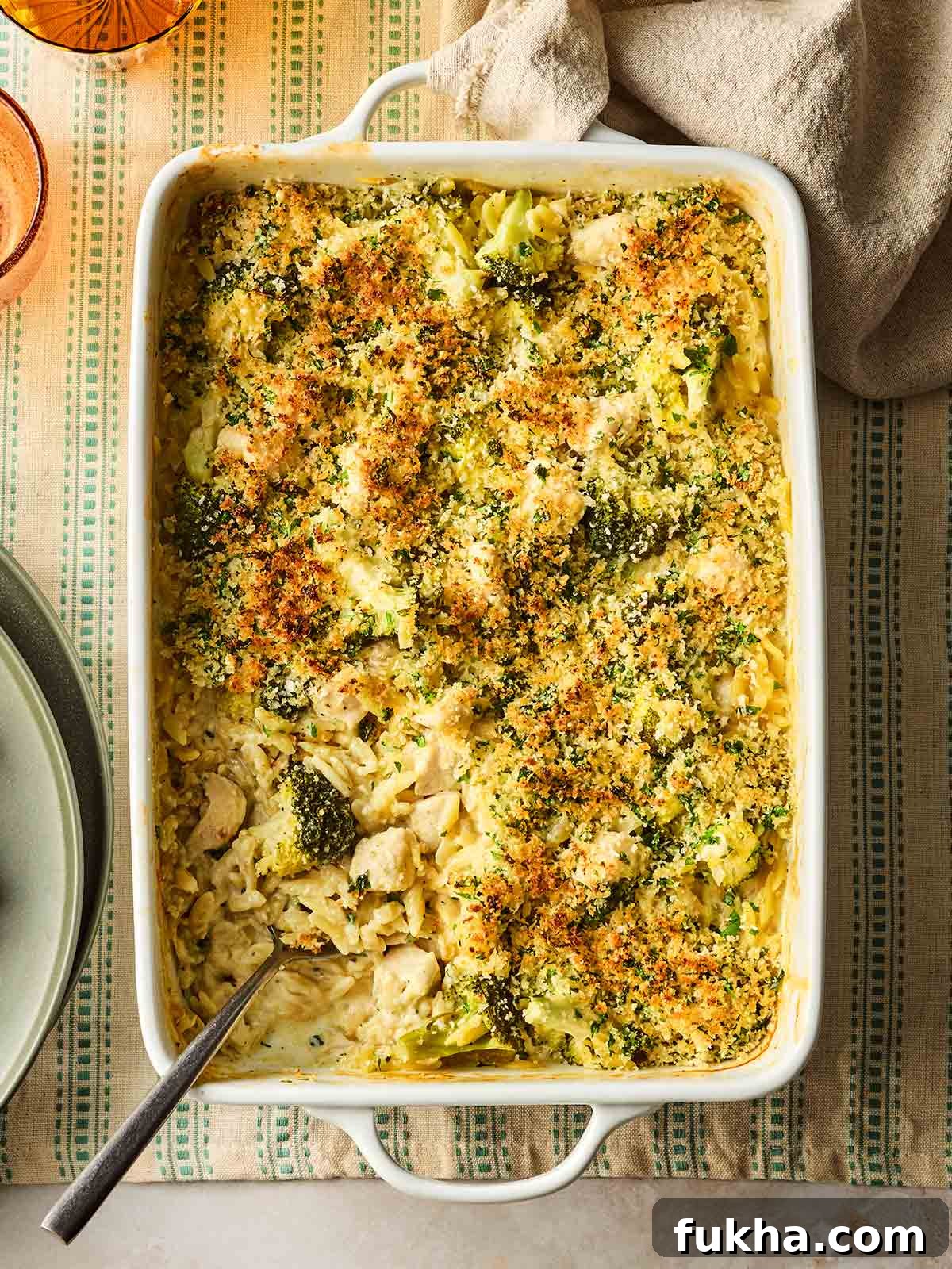 Dump-and-Bake Chicken Kyiv with Creamy Orzo 2 An oven dish on a table with a one pan meal, ready to serve, with chicken, broccoli and orzo in a garlic, creamy sauce.