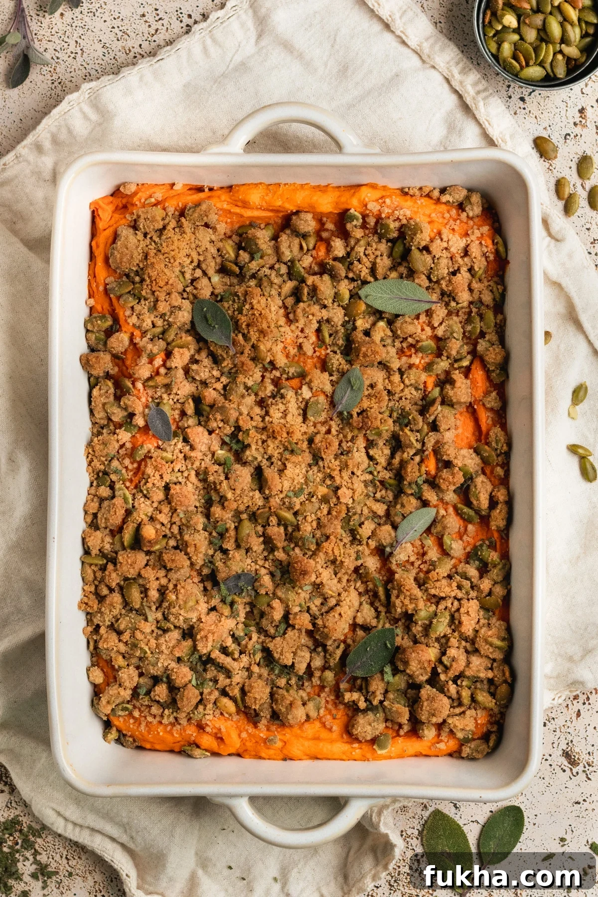 white casserole dish with mashed sweet potatoes & a crumbly topping