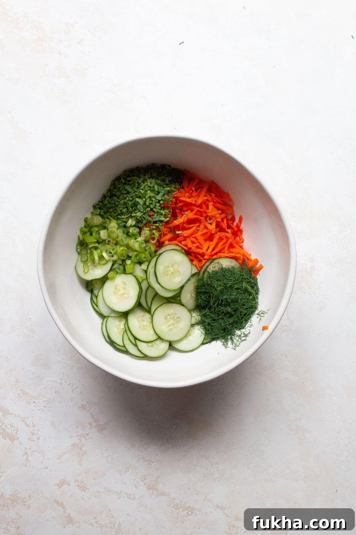 All cucumber carrot salad ingredients in mixing bowl before dressing.