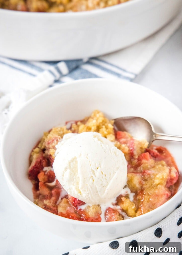 a bowl of strawberry crumble with vanilla ice cream on top