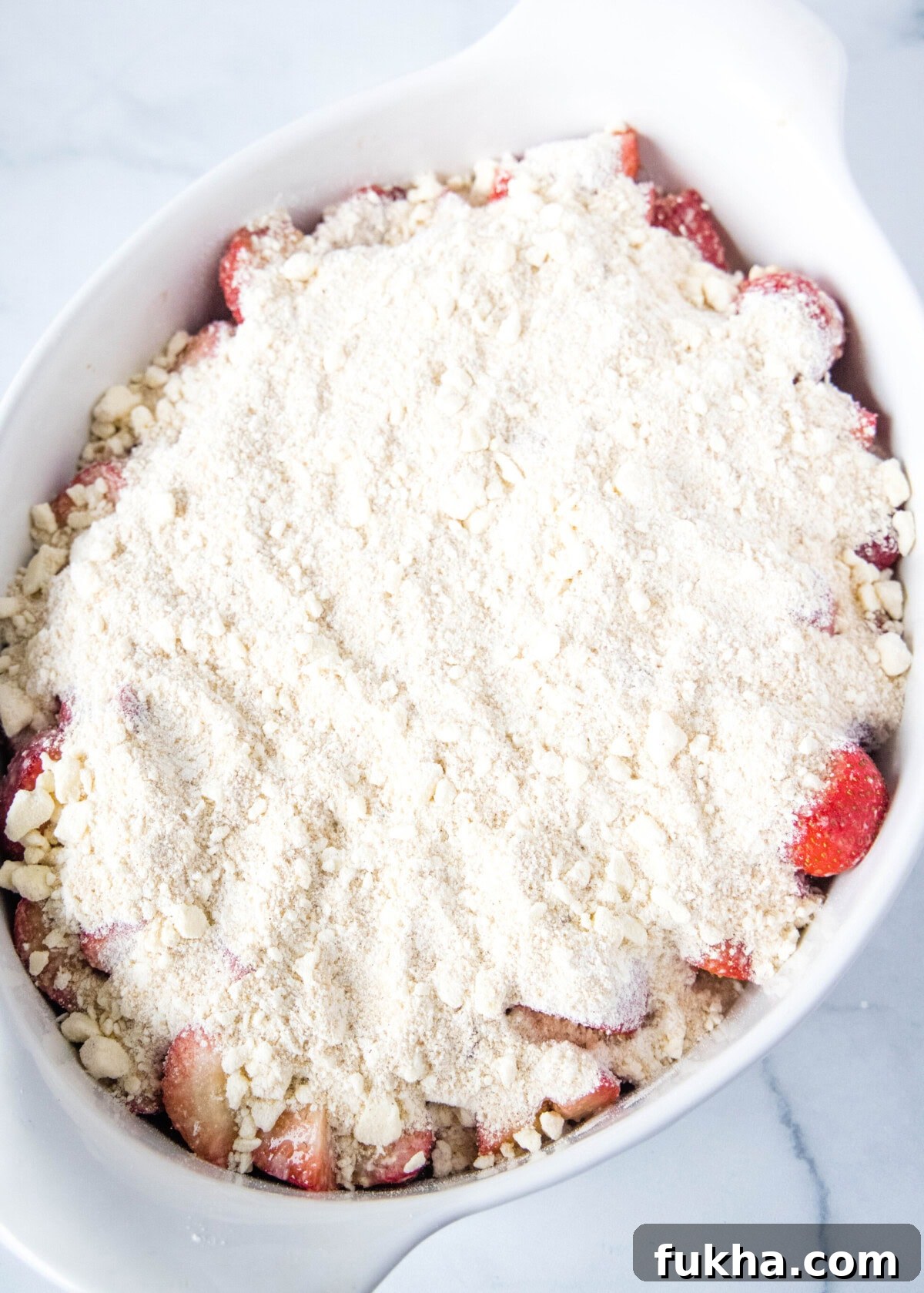 baking dish with strawberries and crumb topping ready for the oven