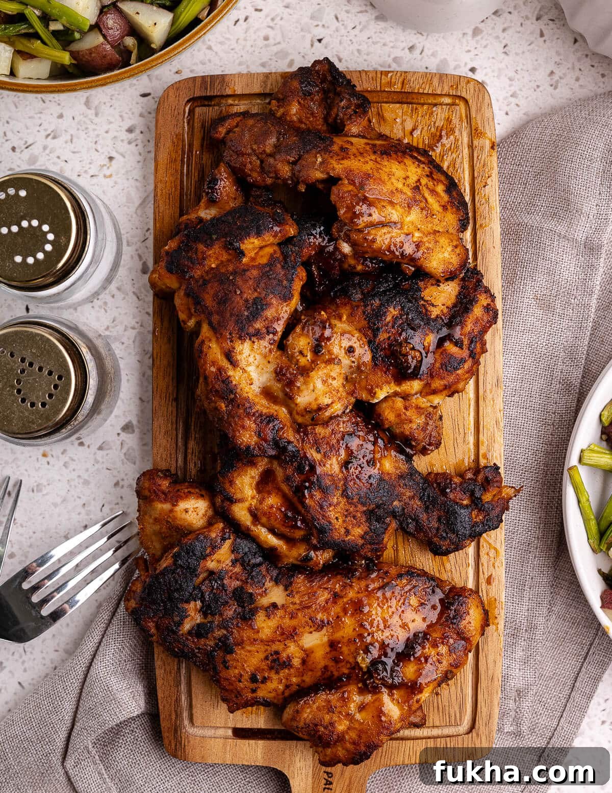 cooked boneless skinless chicken thighs on a cutting board. 