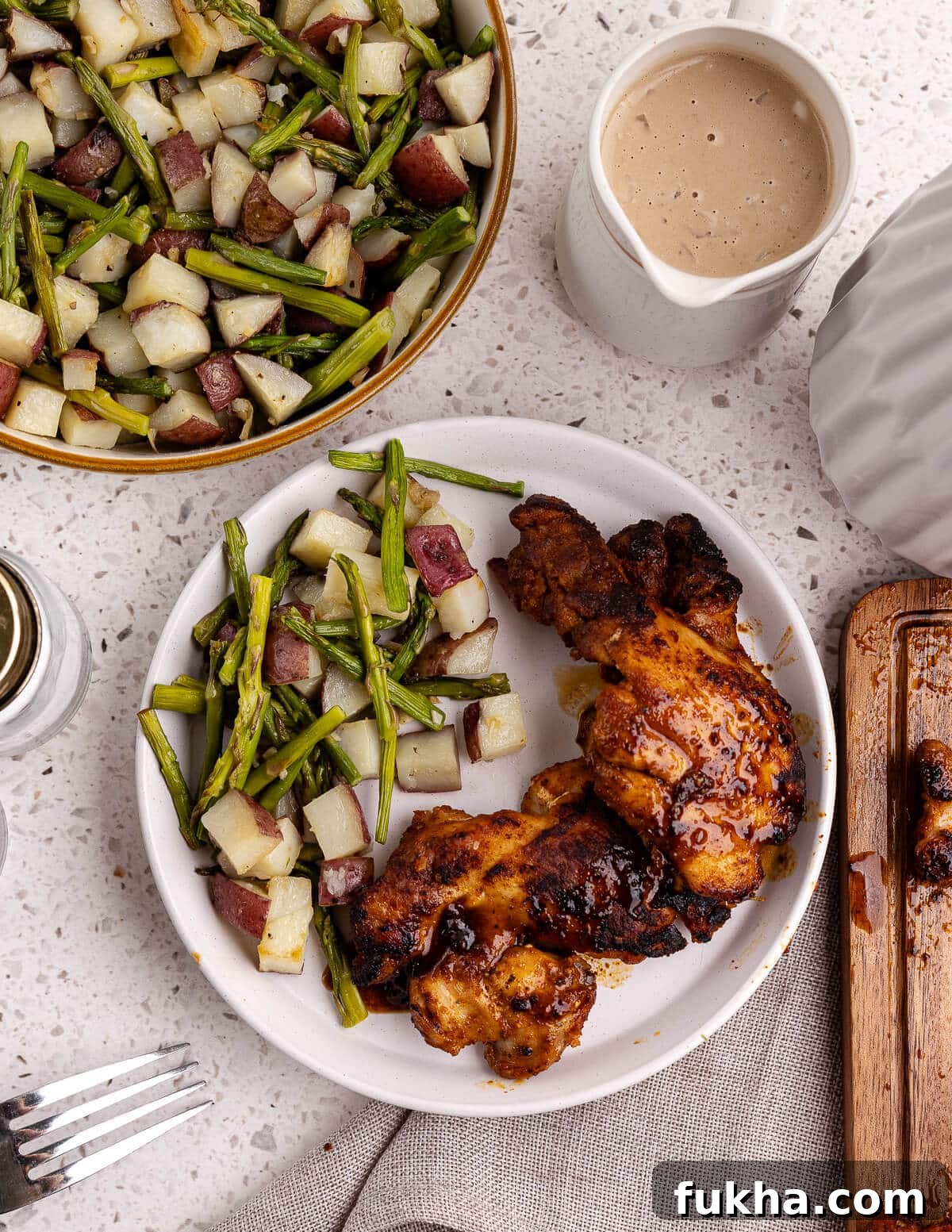 roasted potatoes and asparagus with caramelized chicken on a plate. 