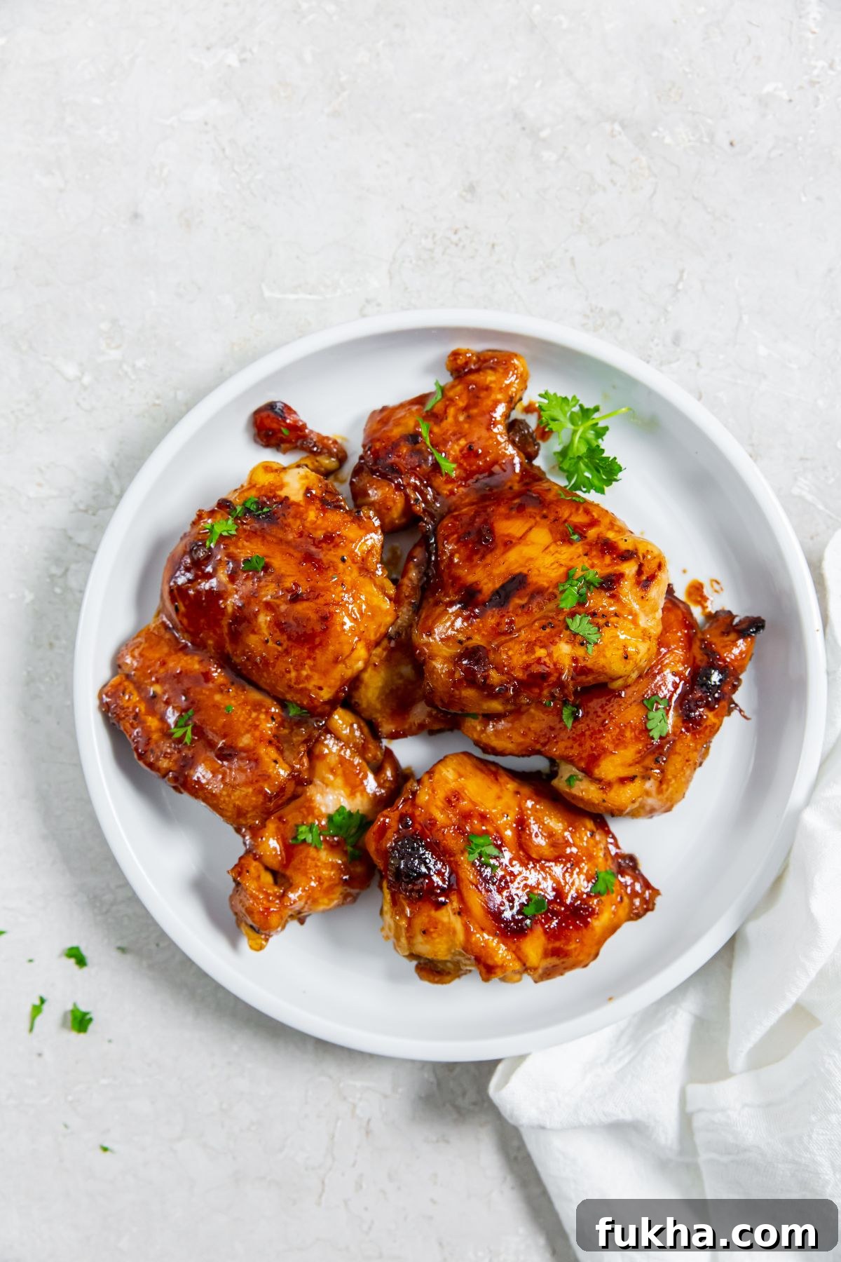 Honey Lemon Pepper Chicken Thighs on a white plate with a white napkin on the side