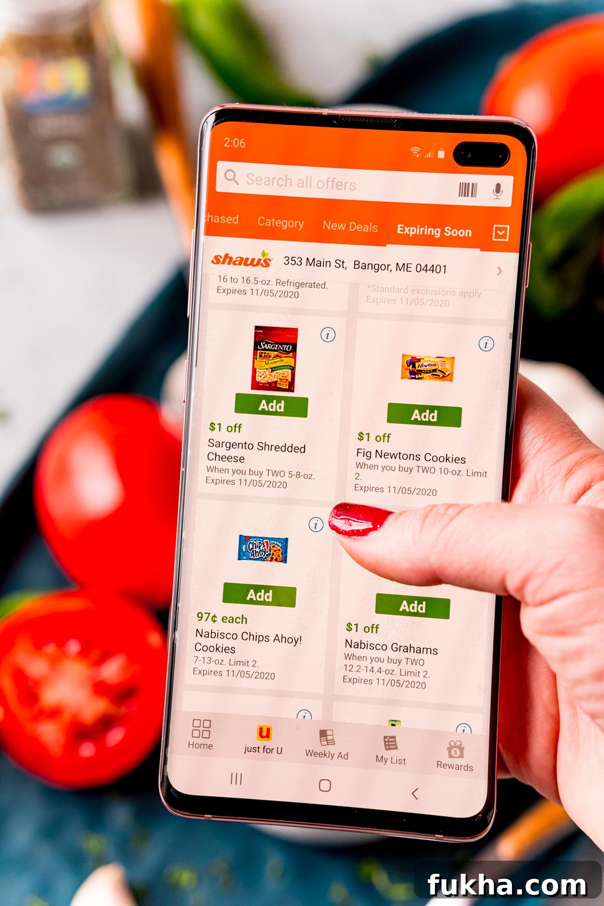 Woman's hand holding a cell phone with the Shaw's Supermarket app pulled up.