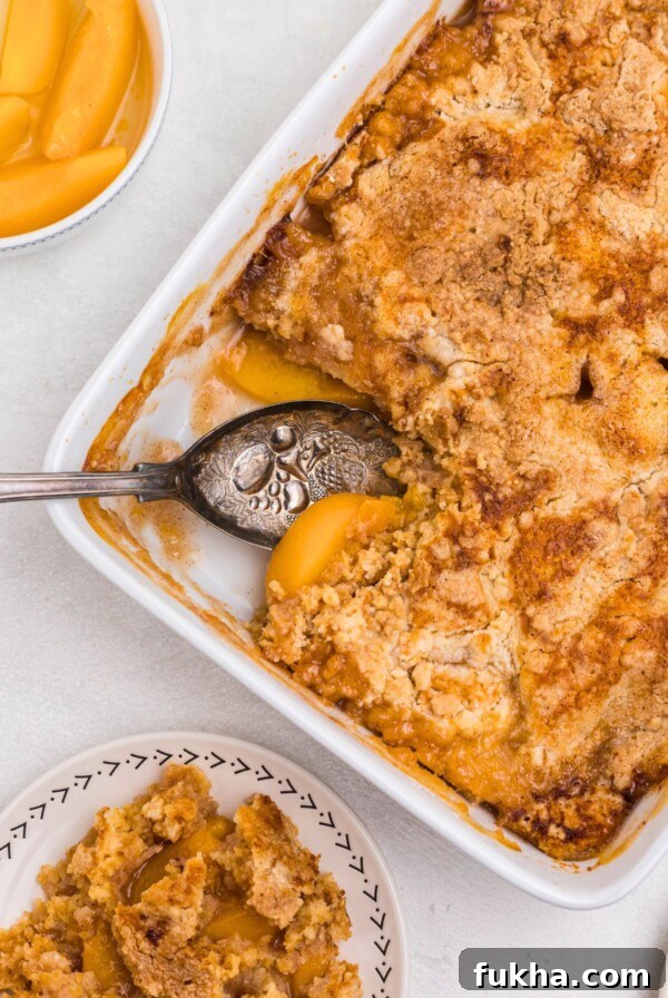 Peach dump cake with a slice spooned out onto s small white plate, with the serving spoon in the dish.