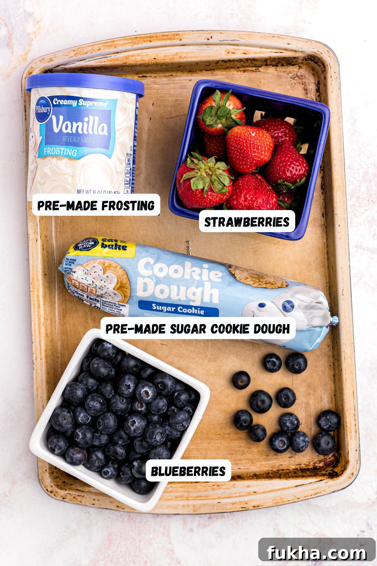 Fourth of July American Flag Fruit Pizza Recipe 3 Cookie dough, frosting, and berries, on a baking sheet.