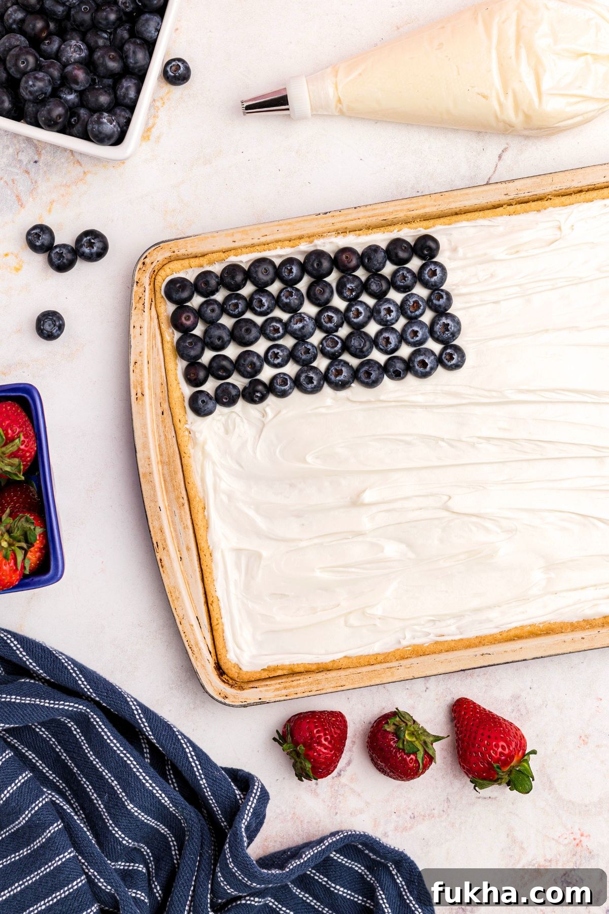 Fourth of July American Flag Fruit Pizza Recipe 6 Fresh blueberries arranged in rows in the top left corner of baked and frosted sugar cookie.