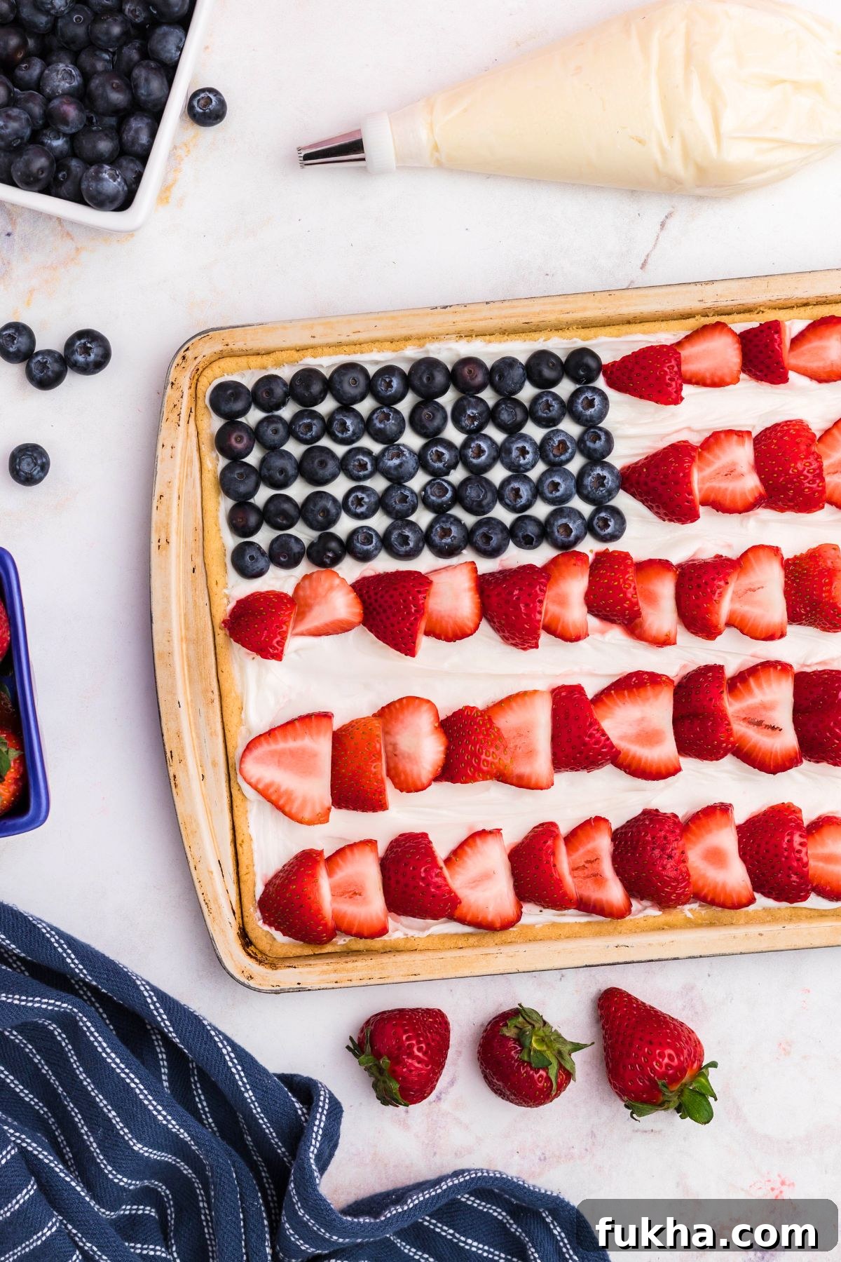 Fourth of July American Flag Fruit Pizza Recipe 7 Fresh strawberry slices being added to frosted sugar cookie to resemble stripes on a flag.