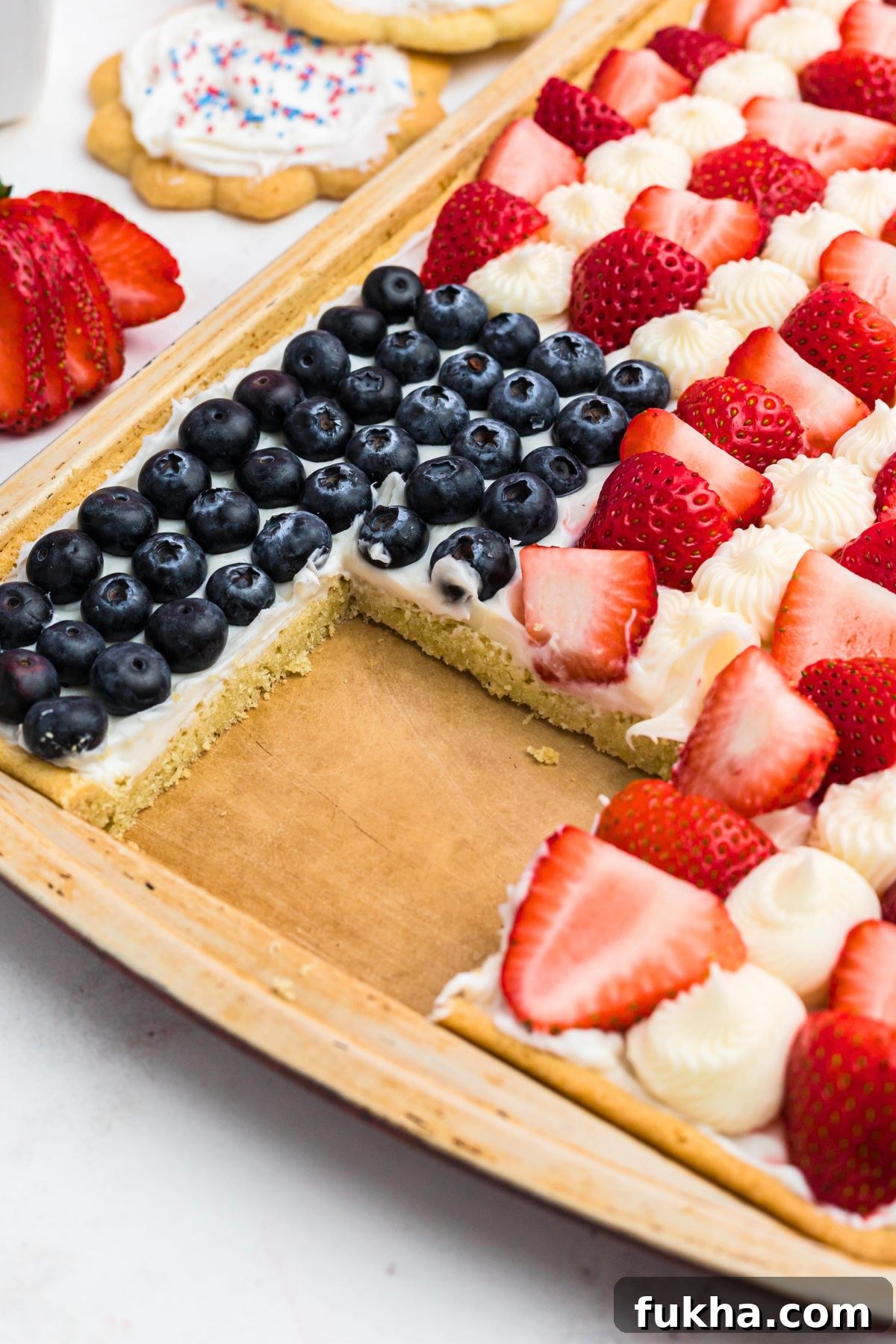 Fourth of July American Flag Fruit Pizza Recipe 9 Frosted flag fruit pizza made from cookie and berries, with a square slice cut out.