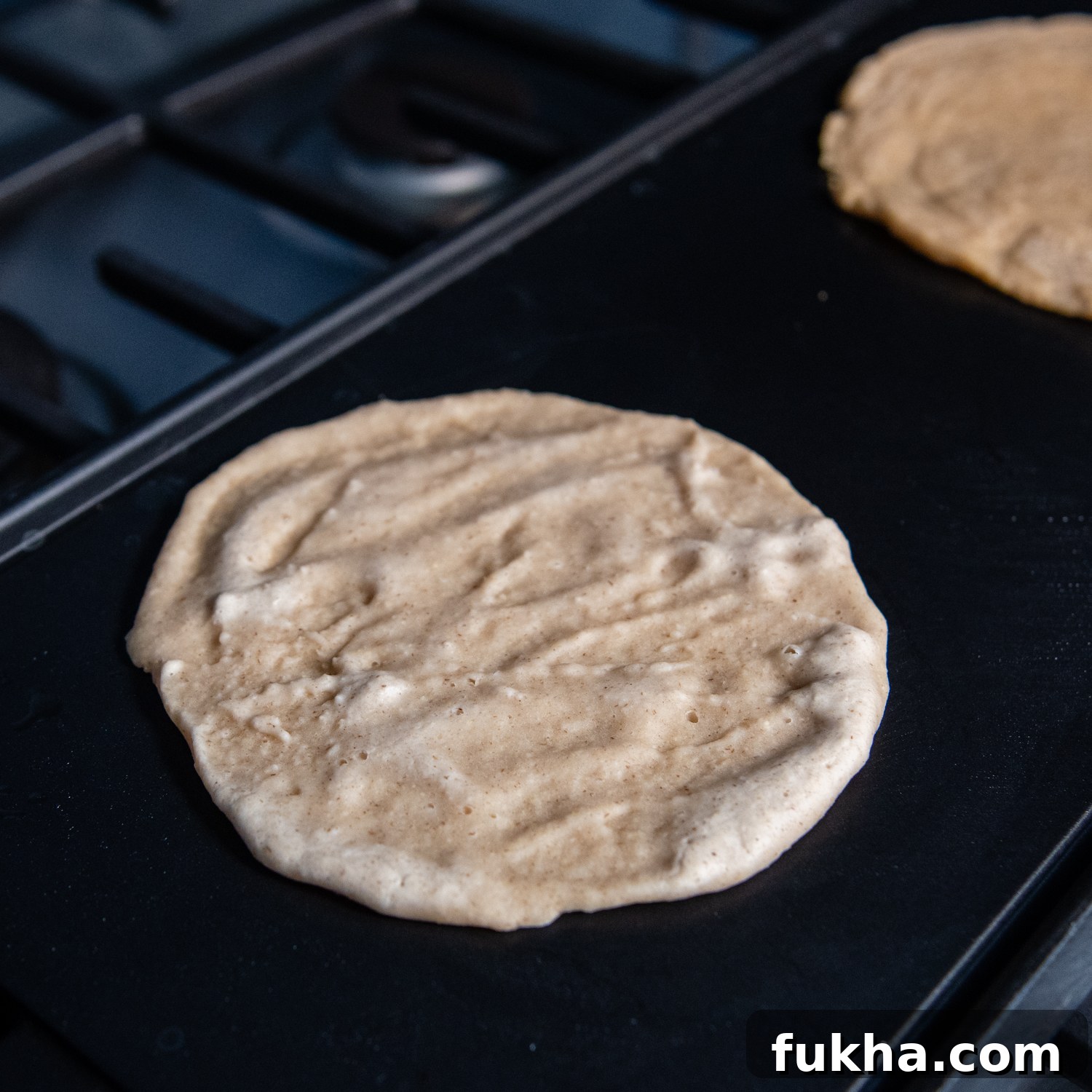 Tortilla mix spread into a circle on griddle.