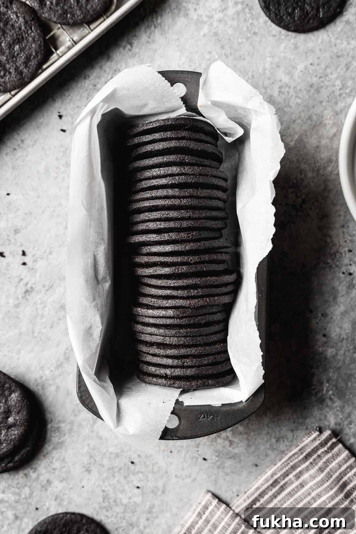 Crispy Homemade Chocolate Wafer Cookies Recipe 2 A row of round dark chocolate cookies in a parchment lined pan.
