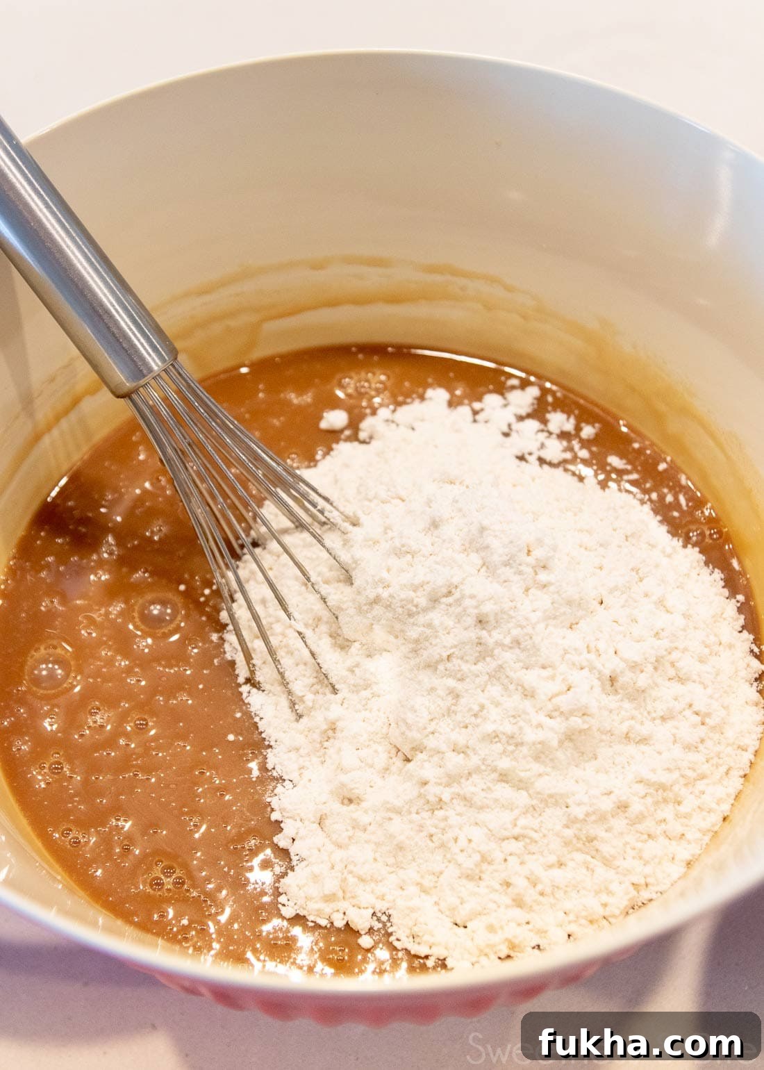 Decadent Caramel Mud Cake Recipe with Gluten Free Option 6 Large bowl with caramel mud cake batter and a balloon whisk.