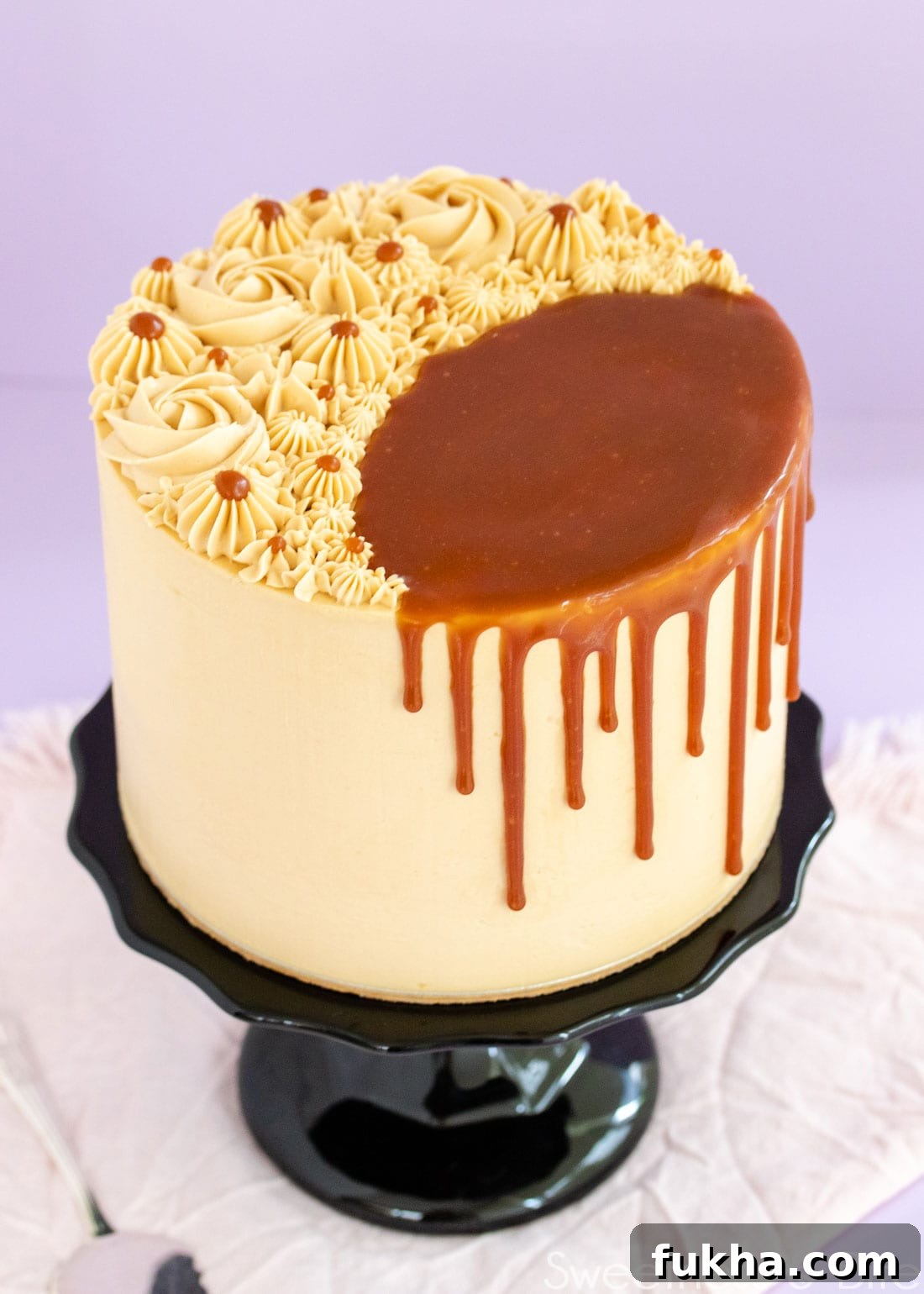 Decadent Caramel Mud Cake Recipe with Gluten Free Option 9 Caramel mud cake on a black cake stand, decorated with swirls of caramel buttercream on top, and a caramel sauce drip.