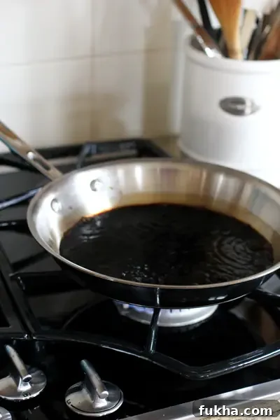 A skillet on a stovetop with simmering balsamic vinegar.