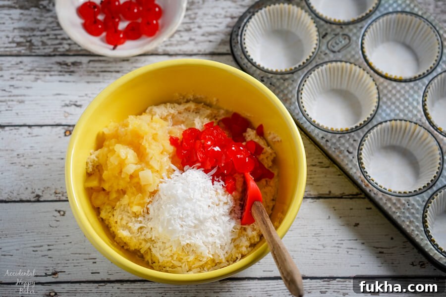 A yellow bowl with muffin batter beside a muffin tin.