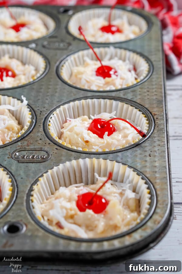 Maraschino cherries and coconut pressed into the tops of the muffins before baking.