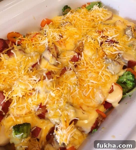 Cheese sauce on top of vegetable, sausage and potatoes in slow cooker
