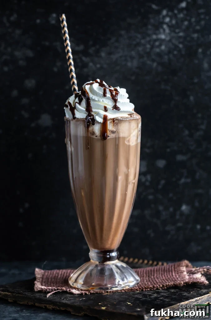 iced mocha served in a tall glass garnished with whipped cream and chocolate syrup