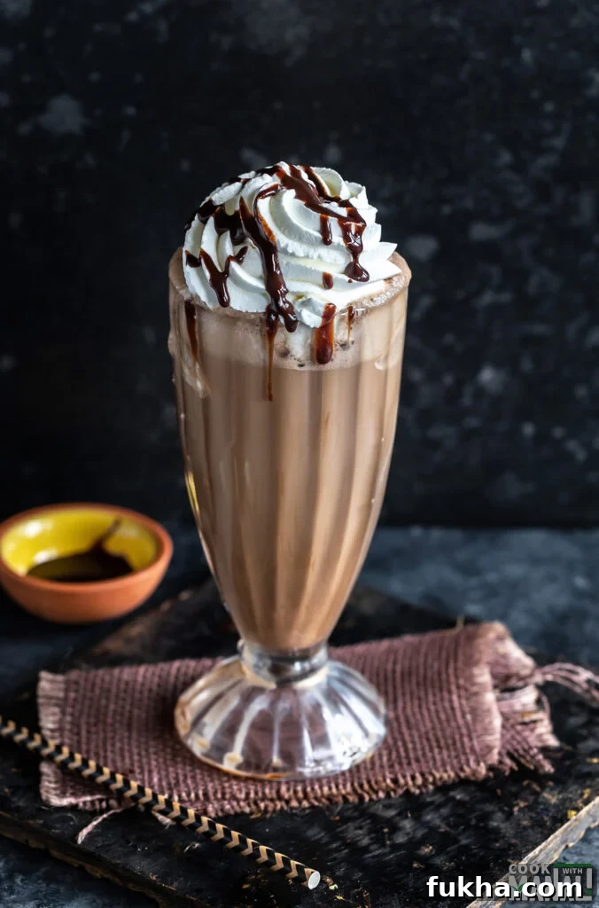 iced mocha served in a tall glass garnished with whipped cream and chocolate syrup