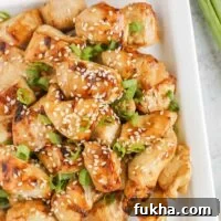 Pieces of air fried teriyaki chicken on a white plate.