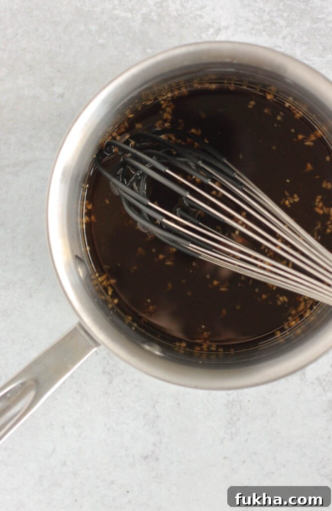Teriyaki sauce ingredients being whisked in sauce pan.