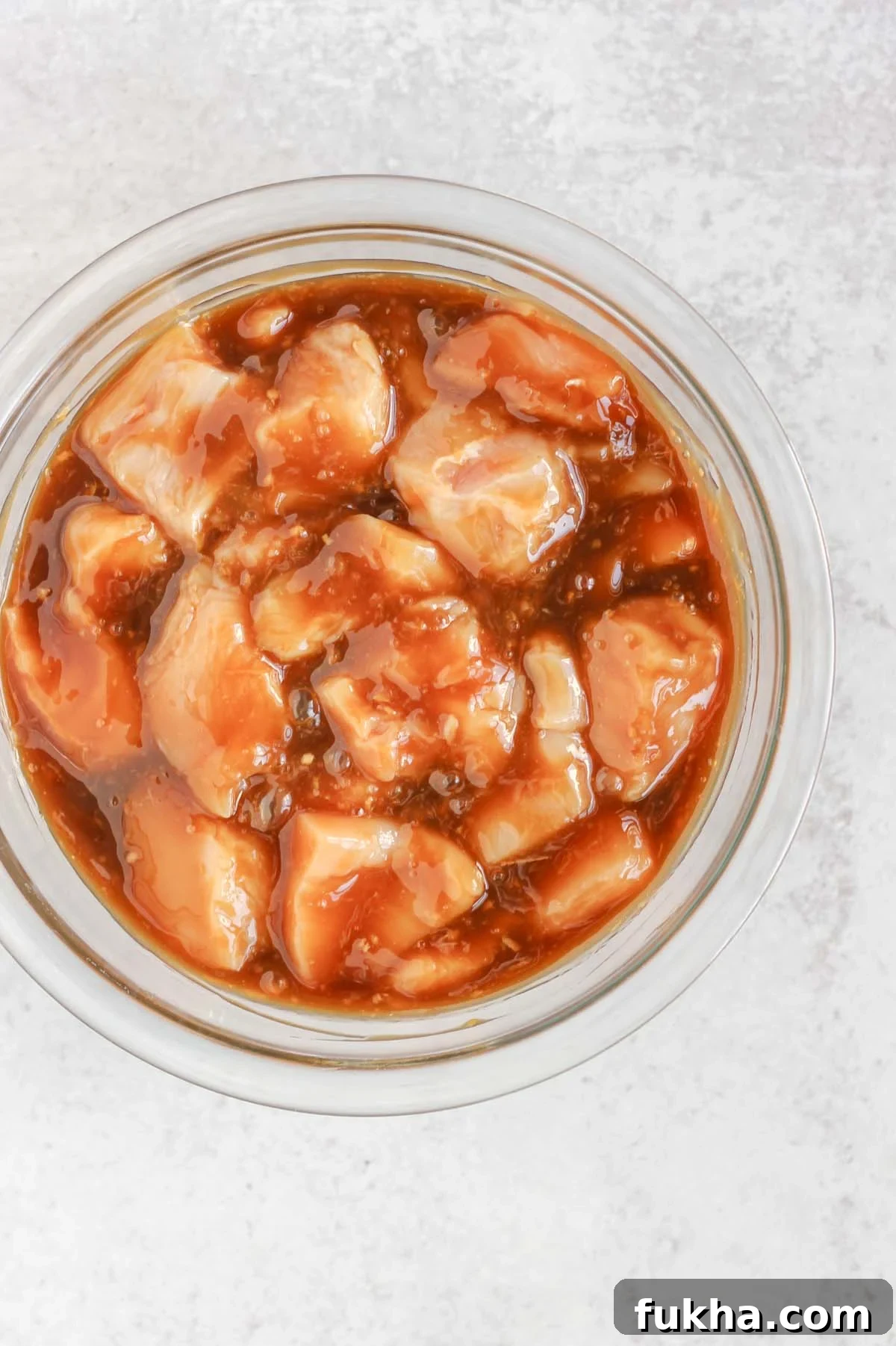 Cut up chicken pieces in a bowl with teriyaki sauce.