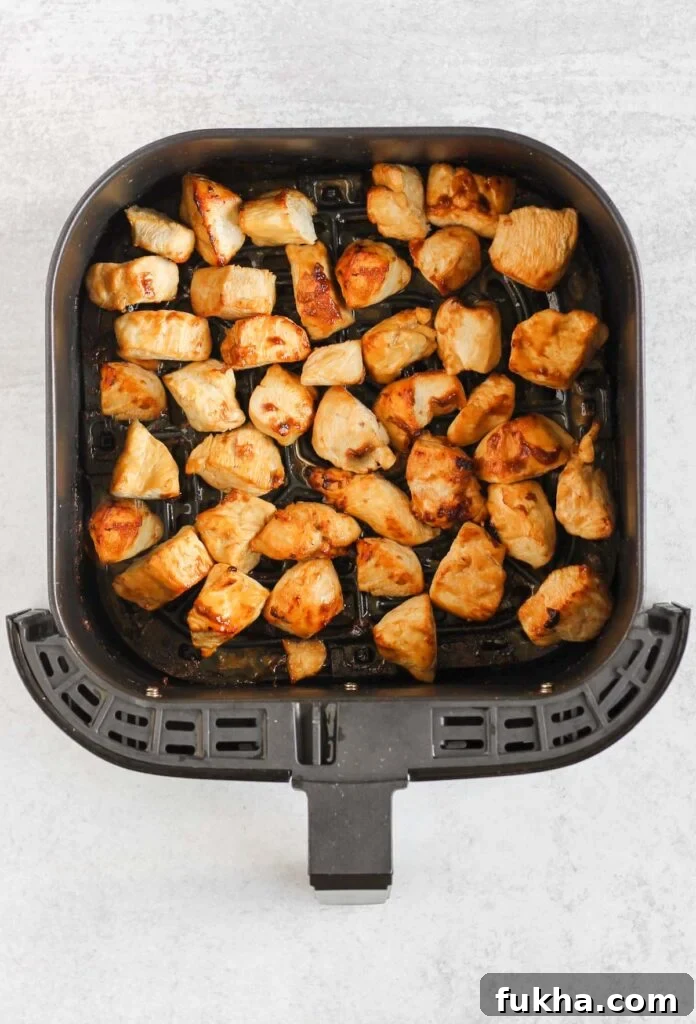 Cooked teriyaki chicken pieces in air fryer basket.