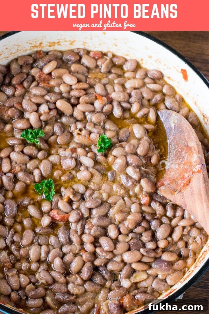 Classic Homestyle Stewed Pinto Beans Recipe 6 Wooden spoon in a pot of stewed pinto beans.