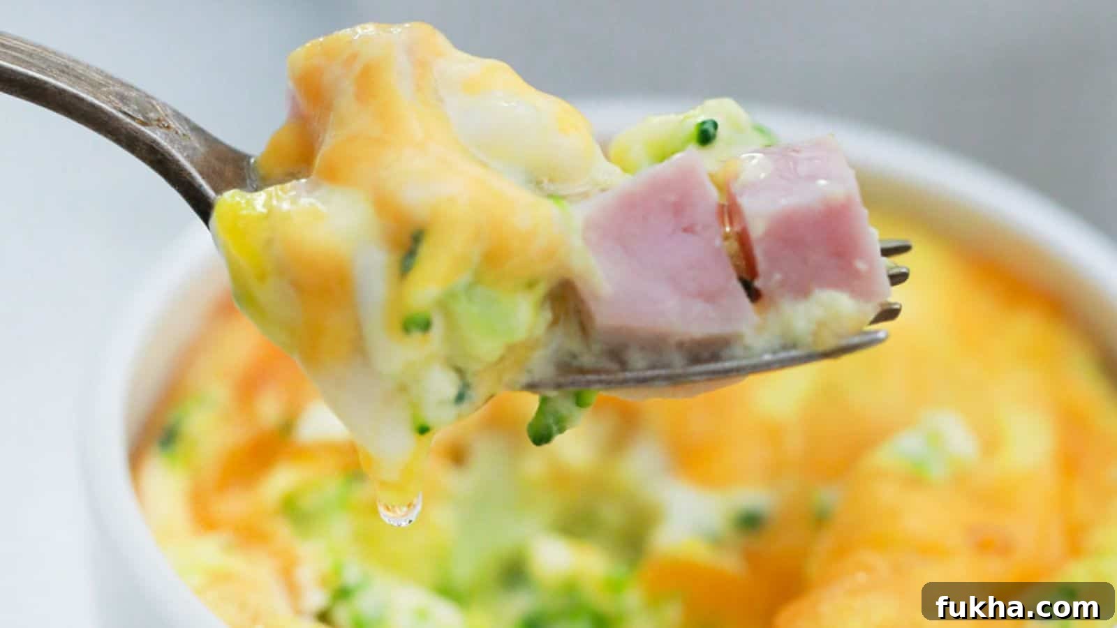 24 Low-Carb Breakfasts to Keep You Full Until Noon 7 A fork holding a bite of mini frittata with ham and broccoli, with the dish in the background.