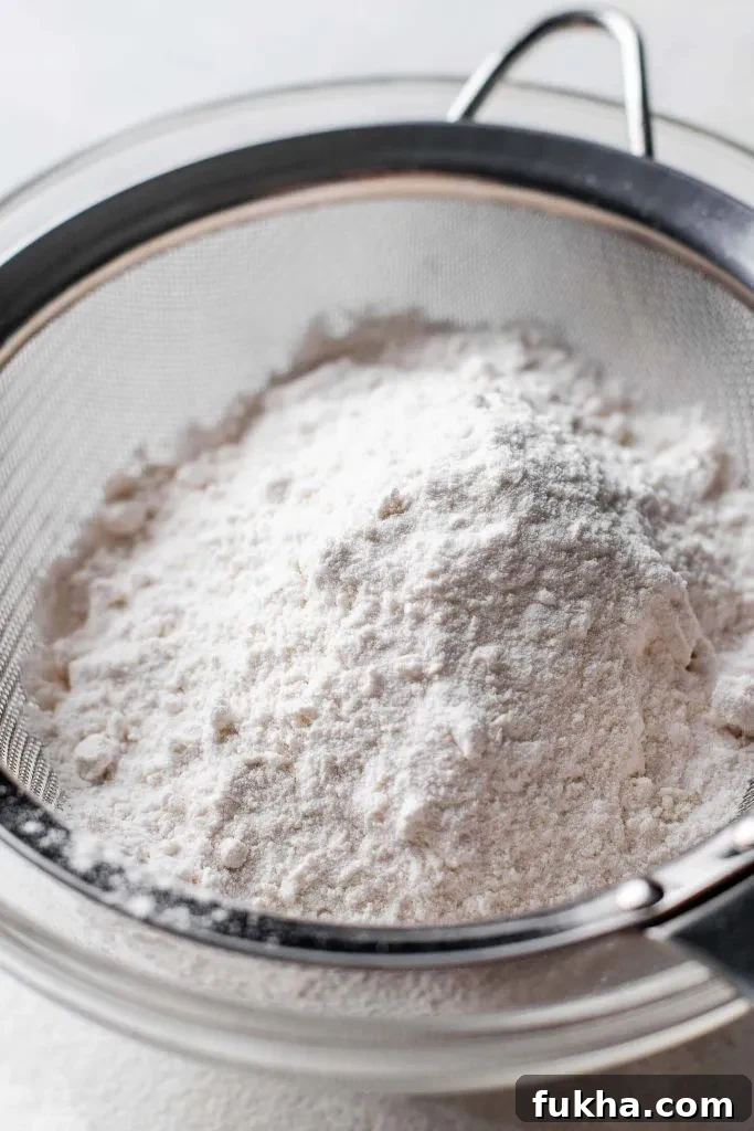 How to Make a Cake and Pastry Flour Substitute 2 cake and pastry flour in mesh sifter set on top of parchment paper