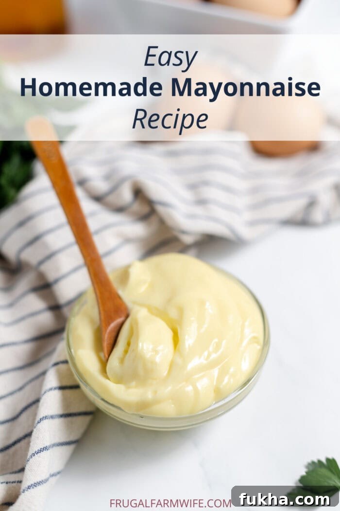 Image shows a small glass dish of mayonnaise with a wooden spoon in it. A towel sits in the background. Text above reads "Easy Homemade Mayonnaise Recipe."