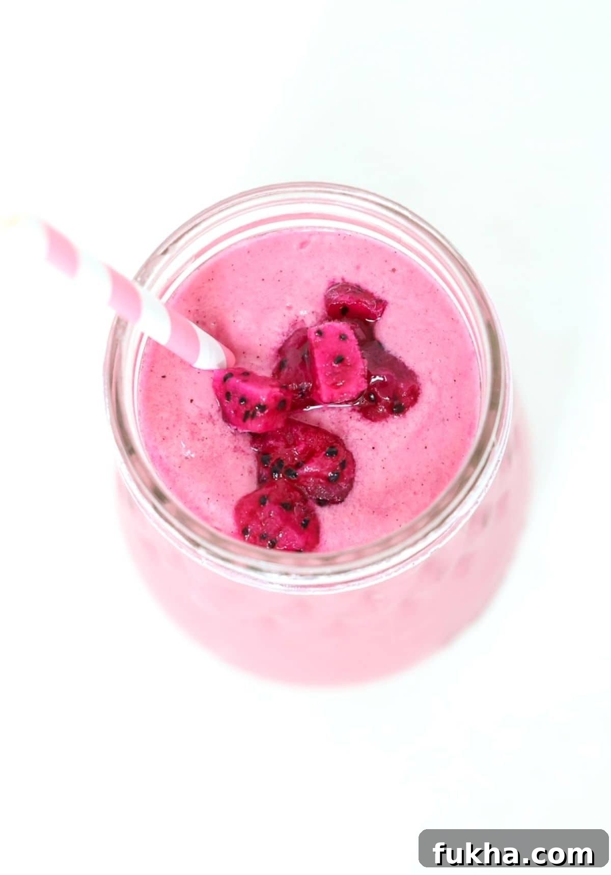 Vibrant Dragon Fruit Smoothie Recipe 2 Top view of a pitaya smoothie in a glass jar with a pink and white striped straw.