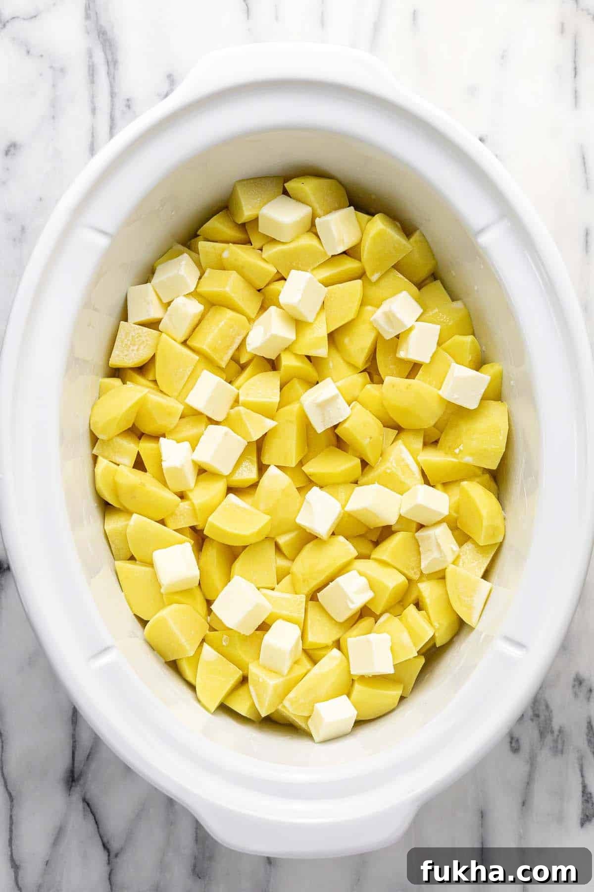 Creamy Slow Cooker Mashed Potatoes 4 Diced potatoes and butter with broth and cream in a large crock pot.