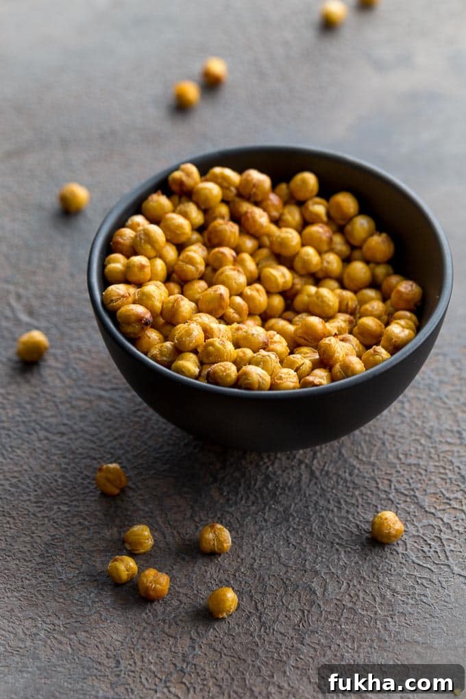 Up-close view of air fryer chickpeas in a black bowl with a few chickpeas scattered around.