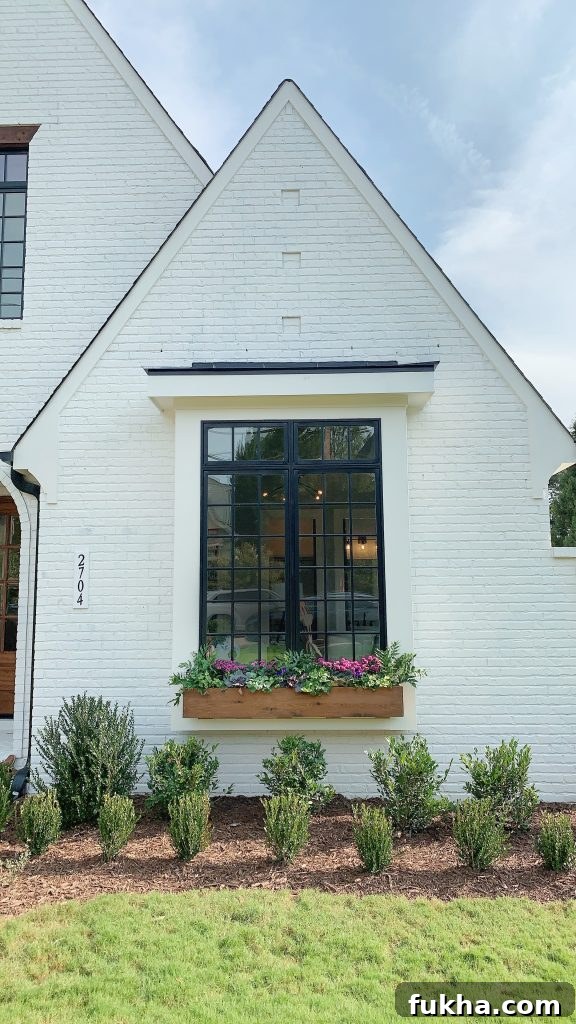 a white brick home with faux flowers for window boxes