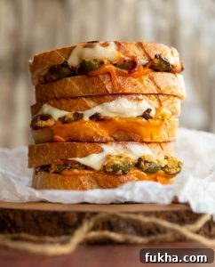 Jalapeno popper grilled cheese 3 sandwich halves stacked on each other on wooden board