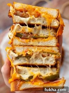 Jalapeno popper grilled cheese sandwich holding 4 sandwich halves close to camera showing filling