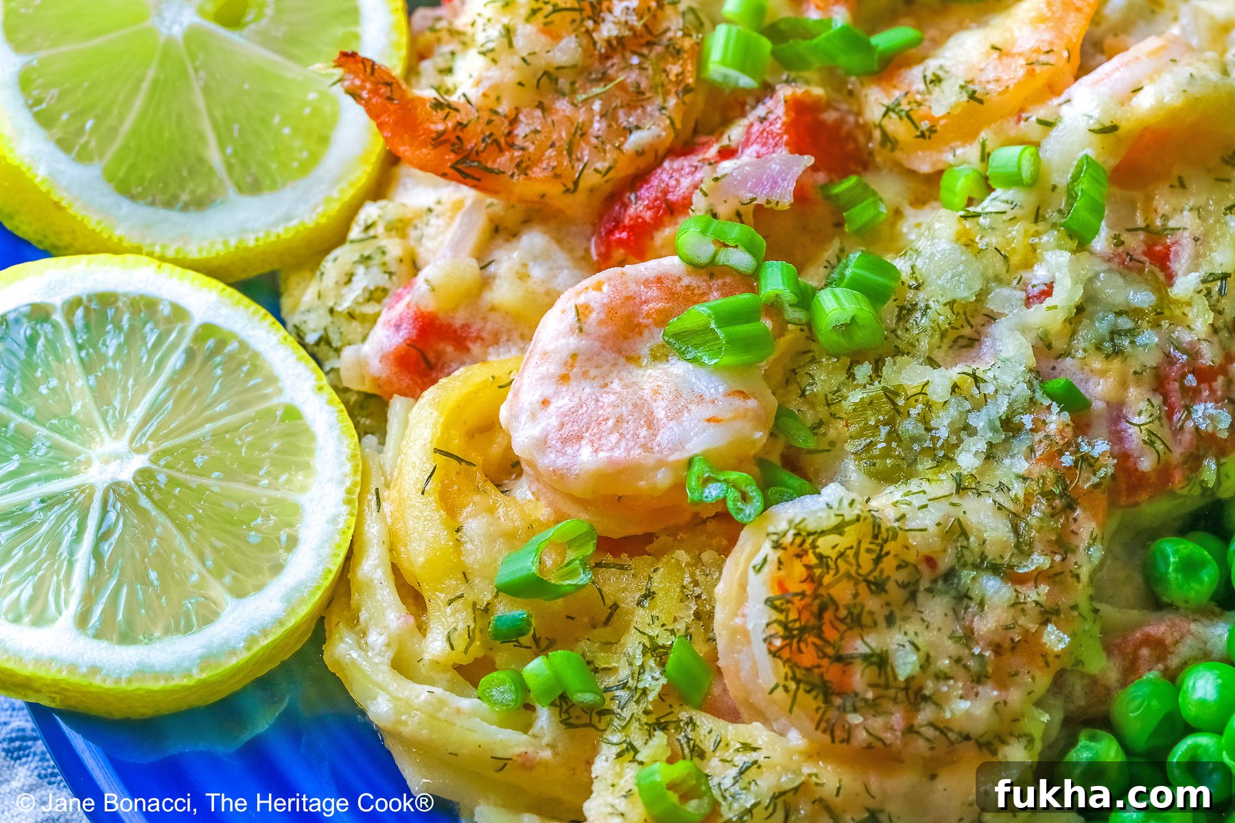 Large scoop of Creamy Dill Shrimp Casserole with shrimp on top and also with peas, yellow squash, and lemon slices on a dark blue plate sitting on a pale blue and white striped cloth © 2025 Jane Bonacci, The Heritage Cook.