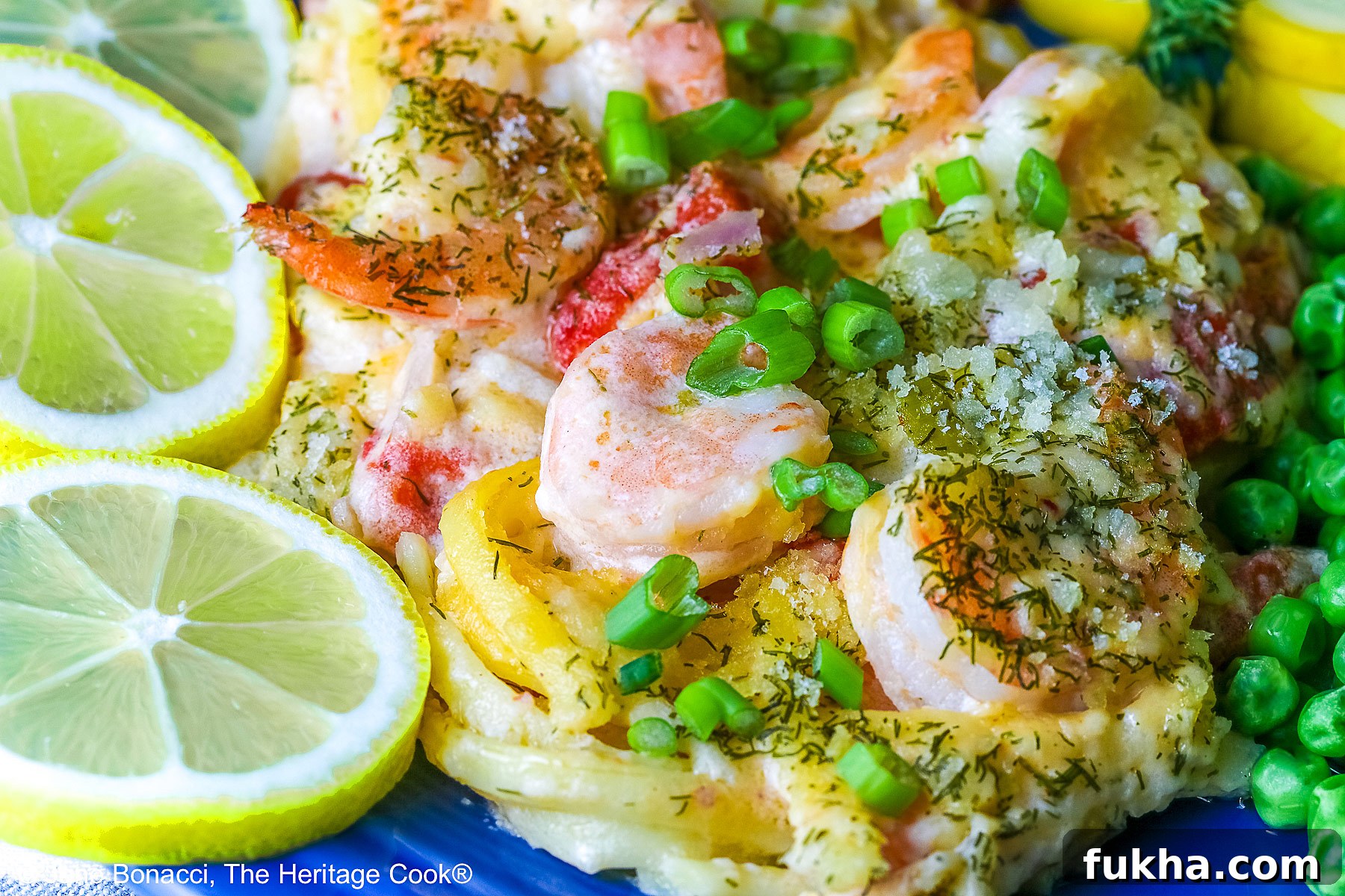 Large scoop of Creamy Dill Shrimp Casserole with shrimp on top and also with peas, yellow squash, and lemon slices on a dark blue plate sitting on a pale blue and white striped cloth © 2025 Jane Bonacci, The Heritage Cook.