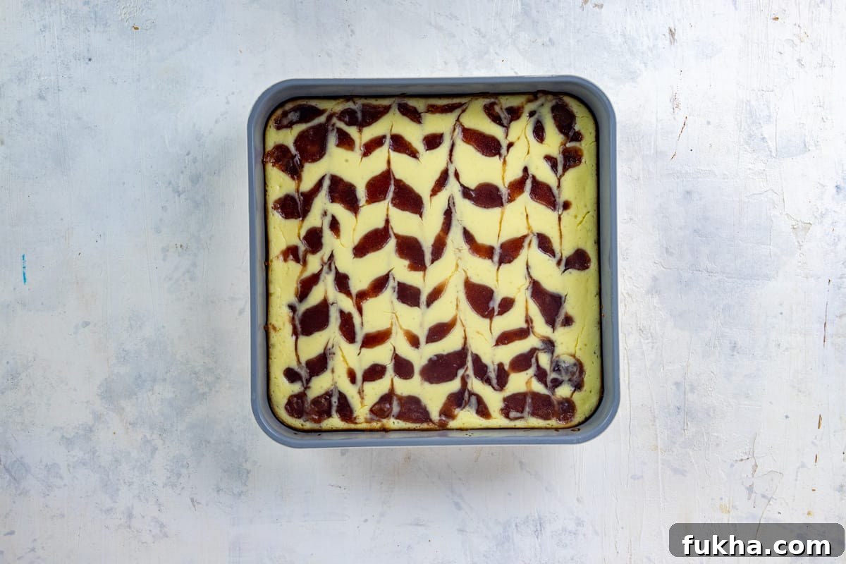 Baked cheesecake with strawberry preserves swirled on top.