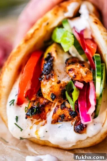 close up of chicken shawarma in naan with cucumber, onion, and garlic sauce.