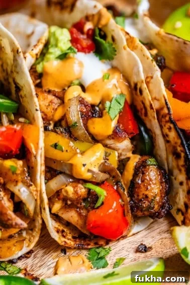 the juiciest chicken fajitas in a warm flour tortilla and topped with guacamole and sour cream.