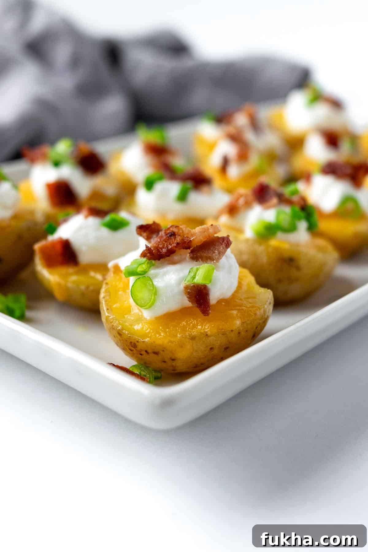 Crispy Baked Potato Bites with Cheddar and Herbs 6 Potato Bites on a white serving plate.