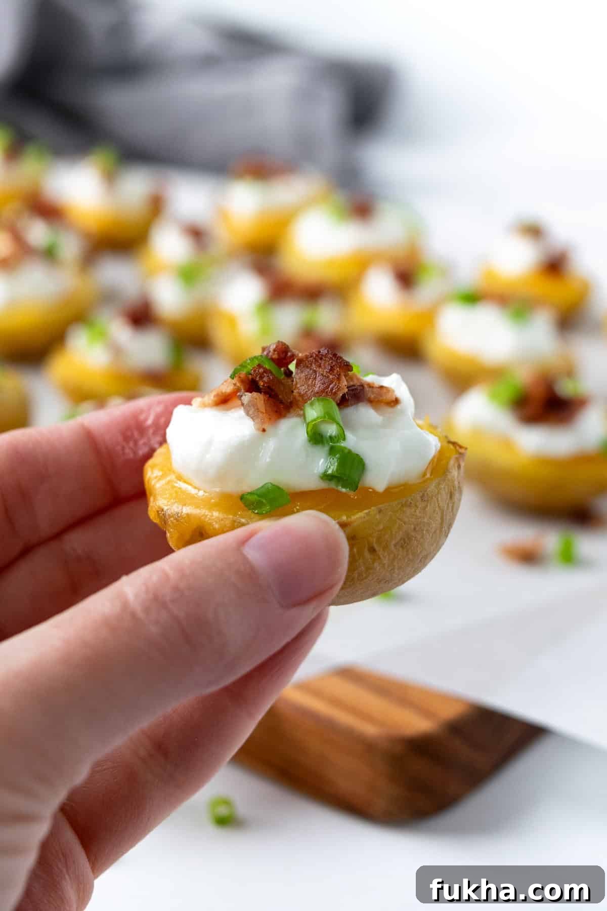 Crispy Baked Potato Bites with Cheddar and Herbs 7 A hand holding a Loaded Baked Potato Bite.