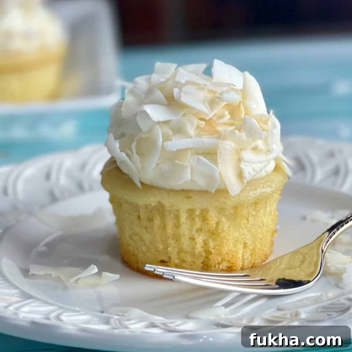 A plate with a Coconut Cream Cupcake with Whipped Cream Frosting
