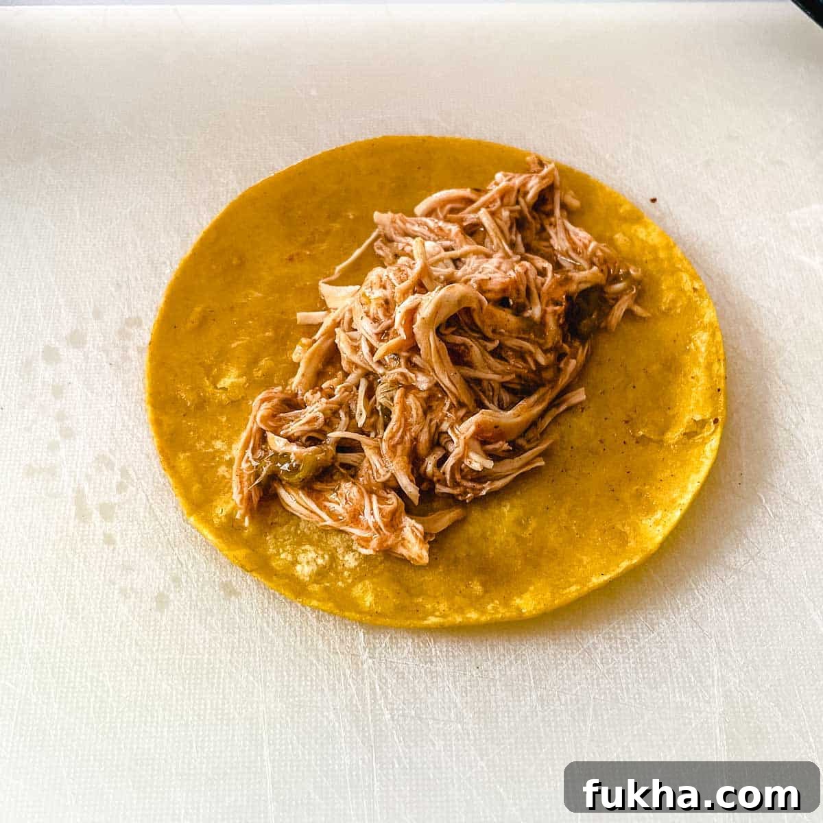 Slow Cooker Shredded Chicken Enchiladas 11 Chicken is added to the tortilla.