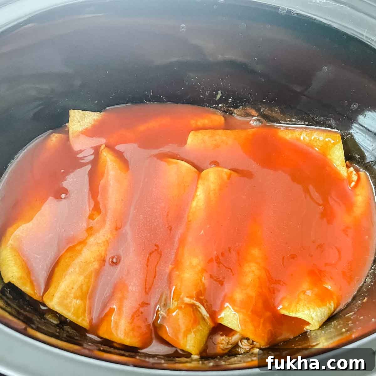 Slow Cooker Shredded Chicken Enchiladas 13 Enchilada sauce is poured over the enchiladas.