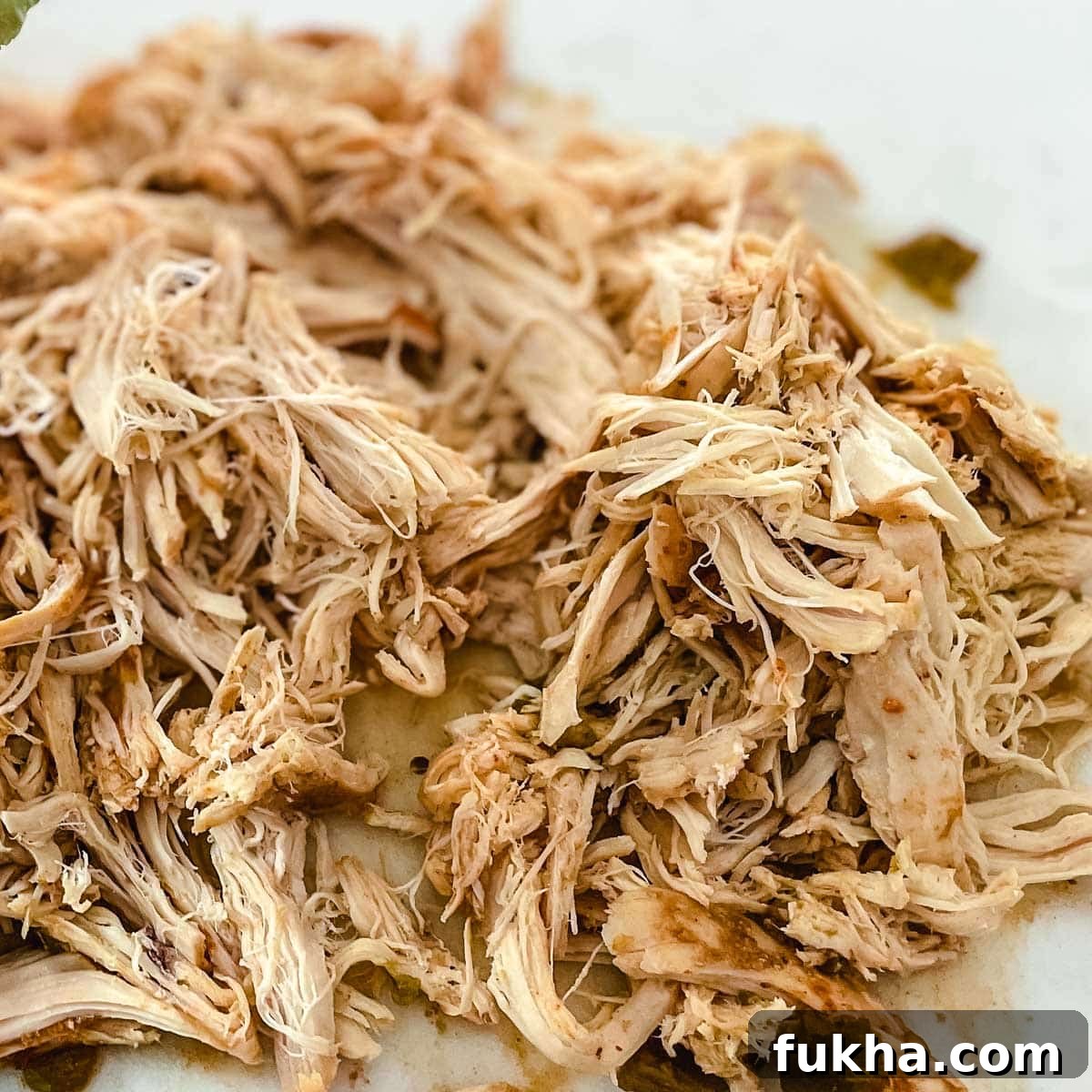 Slow Cooker Shredded Chicken Enchiladas 8 Shredded chicken sits on a white cutting board.