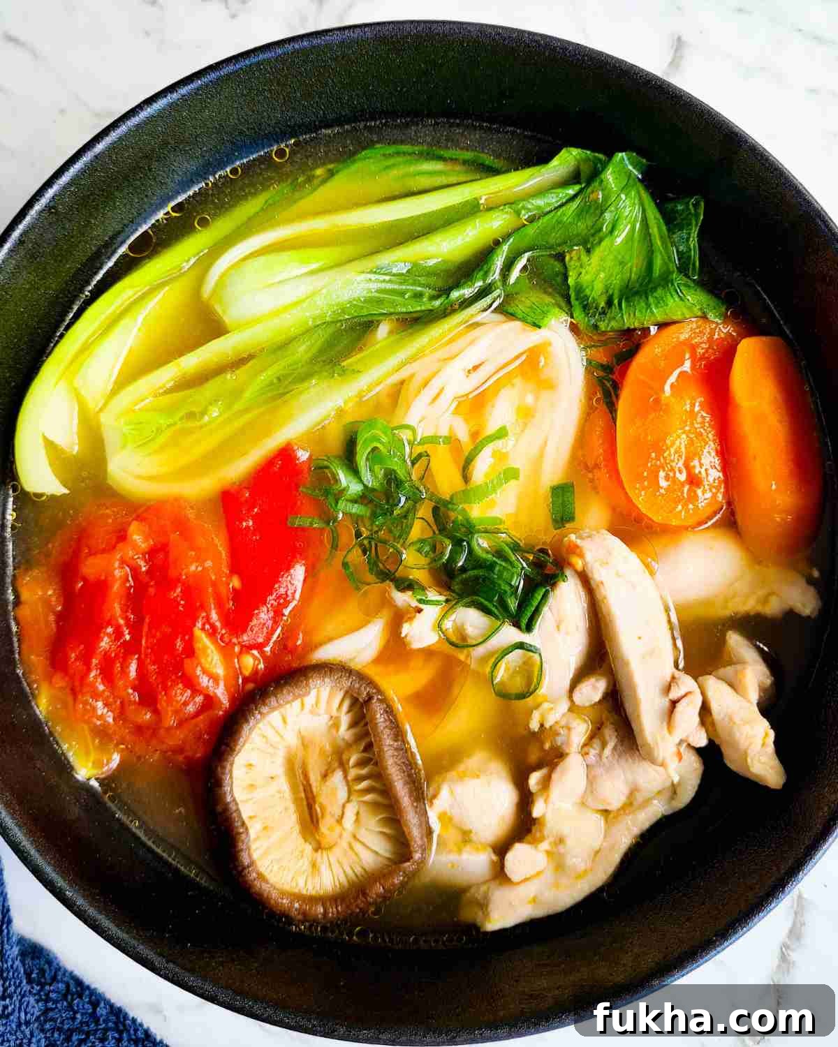 A bowl of noodle soup with chicken and vegetables